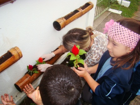 Alunos do Pré ajudando a plantar flores na horta s